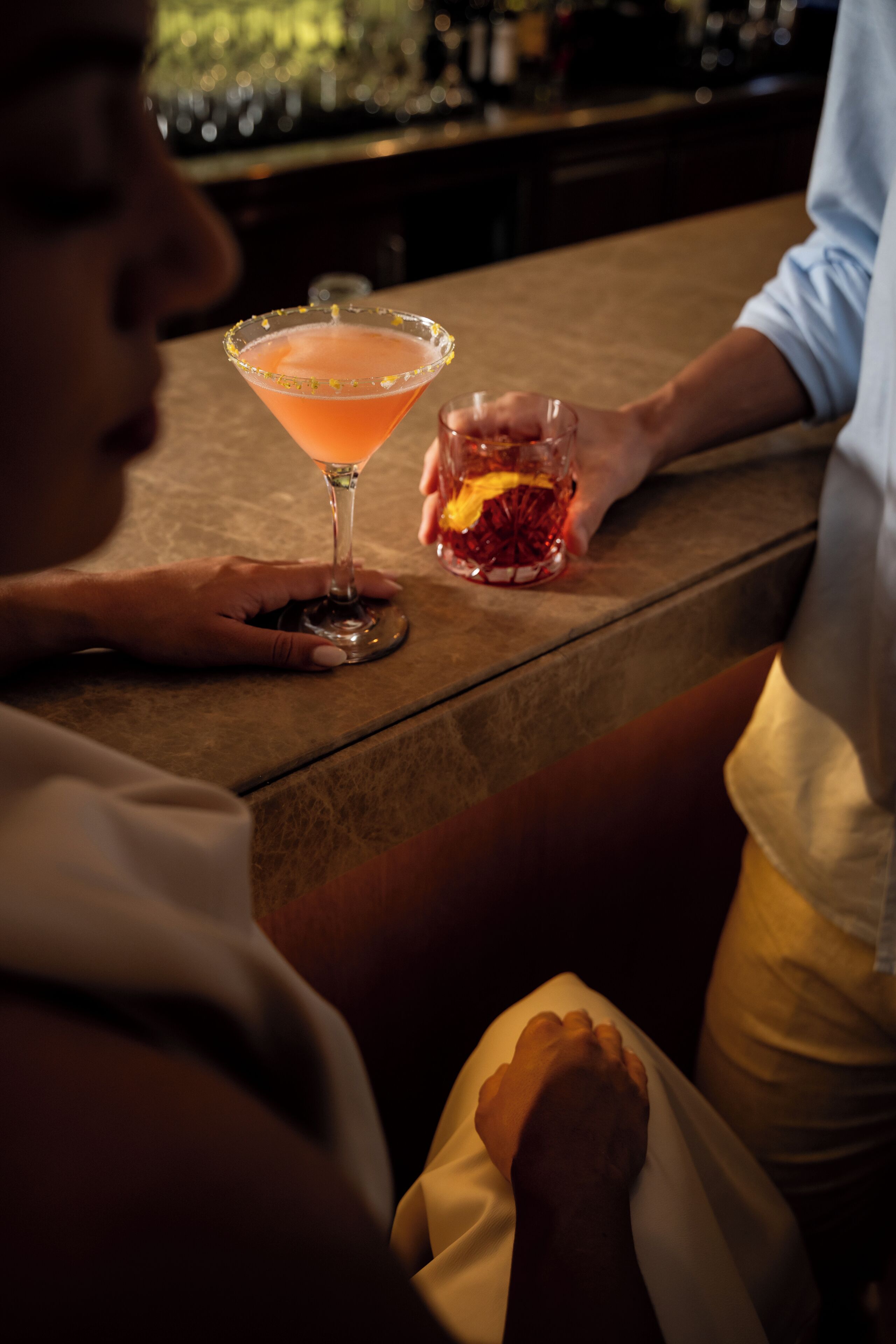 En bardisk med en person som håller i ett cocktailglas.