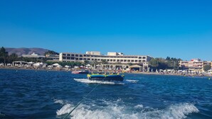 Un hotel frente al mar con zona de piscina, asientos en la playa y vistas al océano.