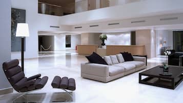 A spacious lobby with a sofa, chairs, a reception desk, and a coffee table.