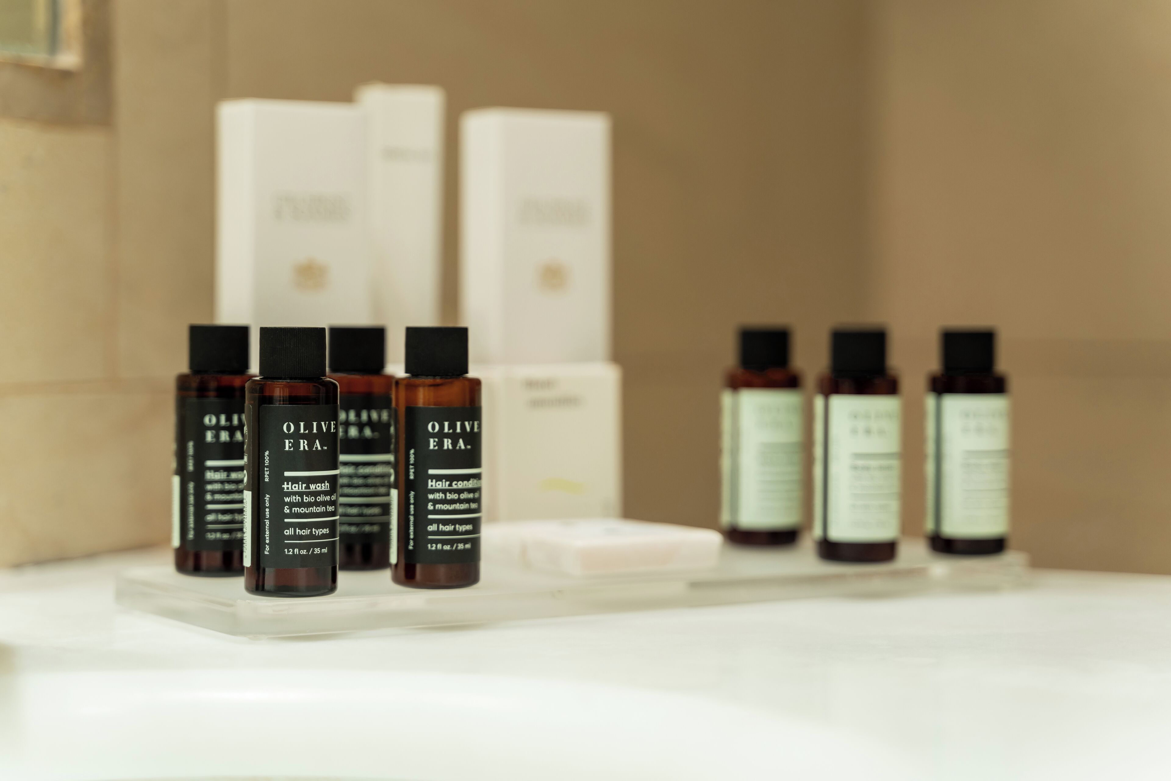 A bathroom shelf with various hair care products, including bottles of olive oil and other toiletries.
