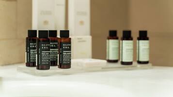 A bathroom shelf with various hair care products, including bottles of olive oil and other toiletries.