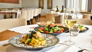 Una mesa con platos de comida, una copa de vino y una vela.