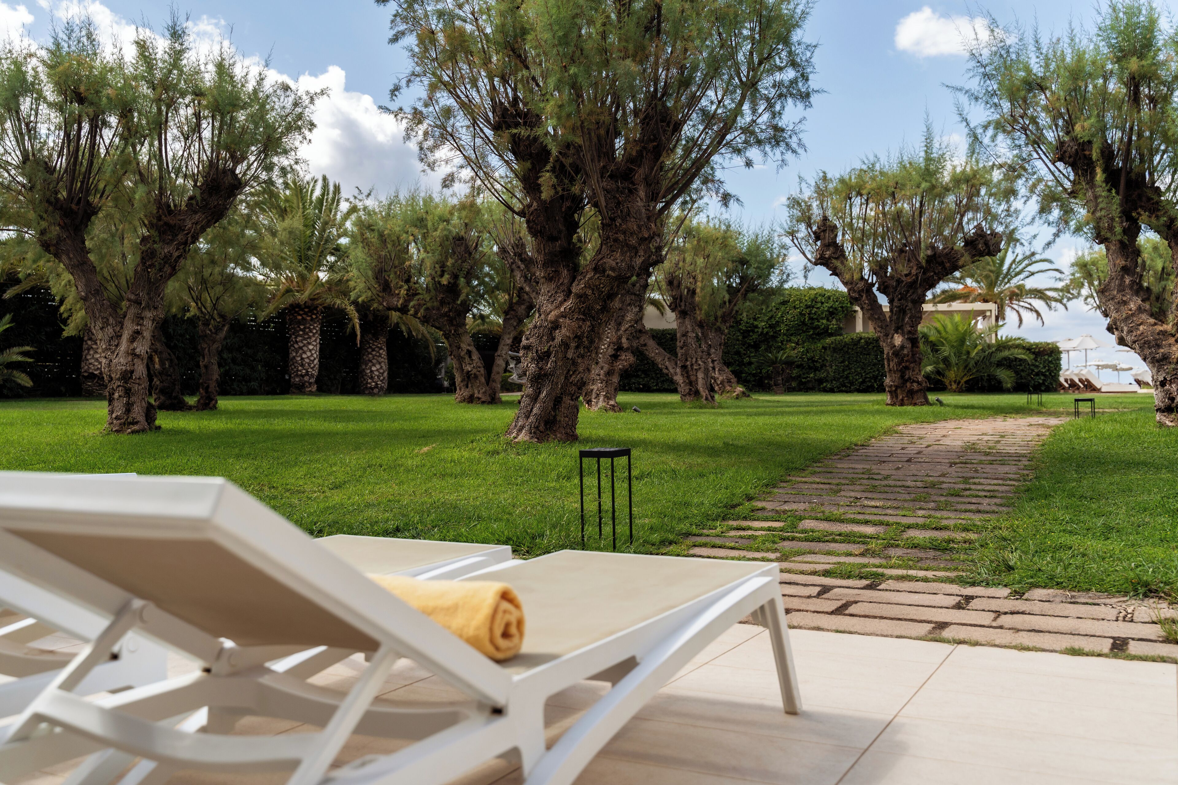 A garden with lounge chairs and a paved path.