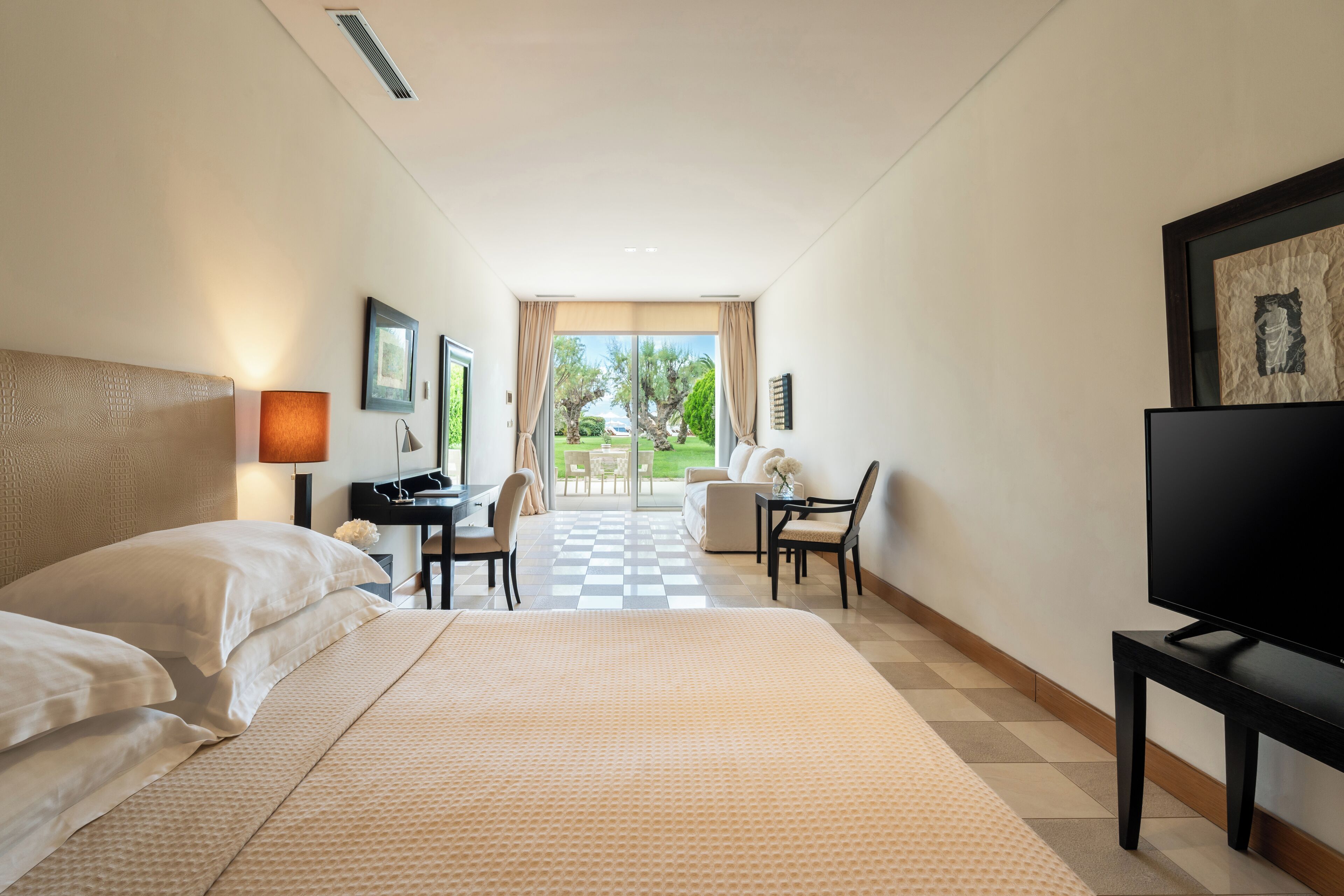 A hotel room with a large bed, a desk, a television, and a view of the outdoors.