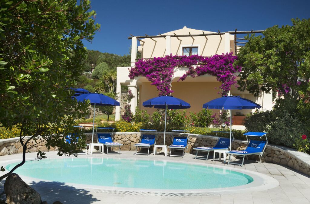 Una piscina al aire libre, sombrillas, sillones reclinables de piscina