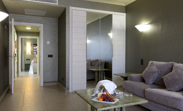 A modern living room with a sofa, a coffee table with fruit, and a mirrored closet. - Hotel Colón Guanahaní Adults Only (Adeje)