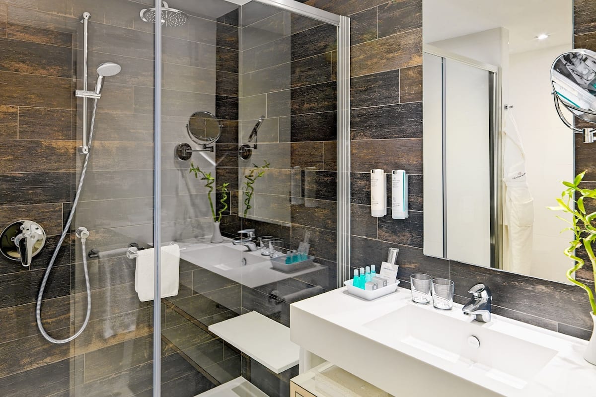 A modern bathroom with a glass-enclosed shower, a white vanity, and a large mirror.