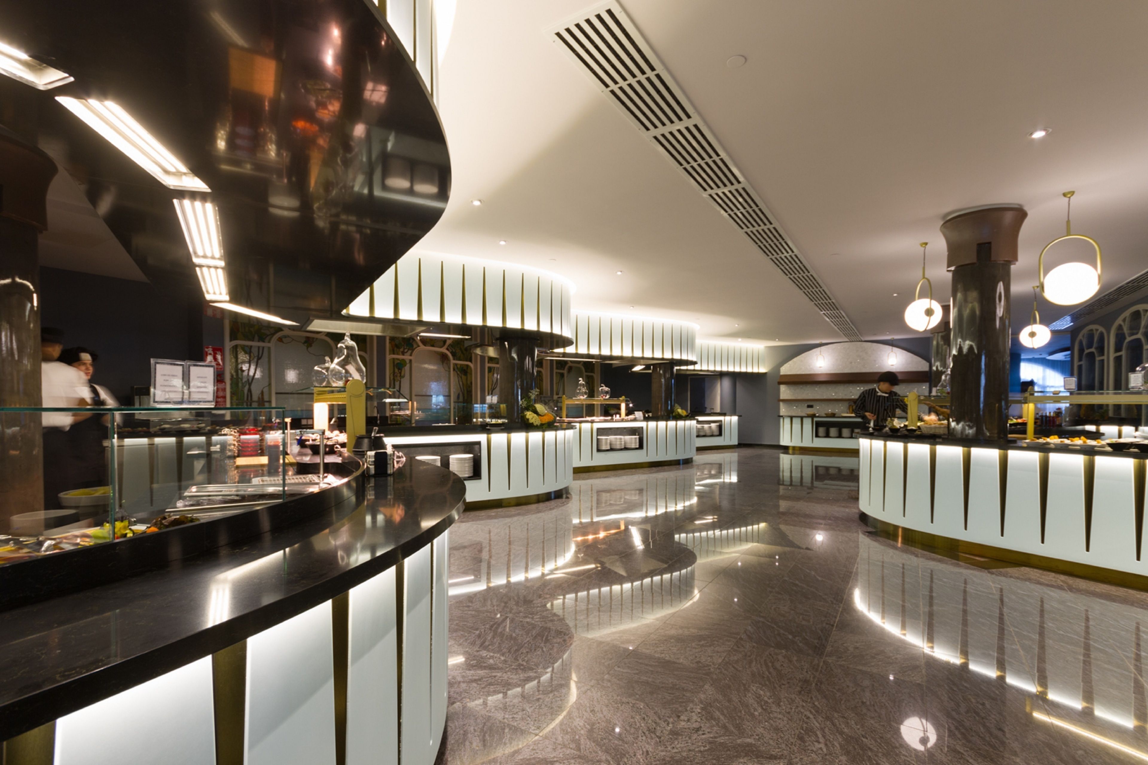 Un restaurante moderno con una barra elegante y curvada y un piso de mármol pulido.