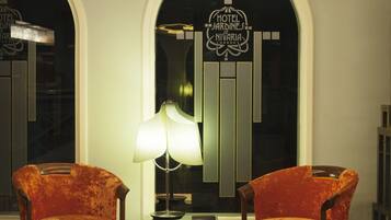 A lobby with two orange armchairs, a table, and a lamp.