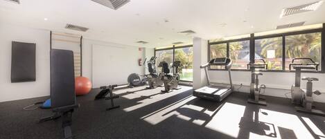 A gym with treadmills, stationary bikes, and exercise balls.