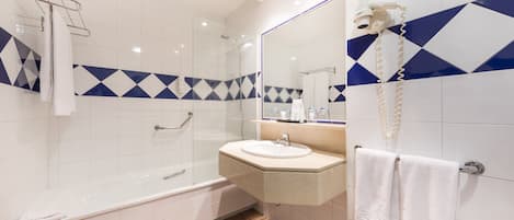 Un baño moderno con cabina de ducha acristalada, tocador con lavamanos y un espejo grande.