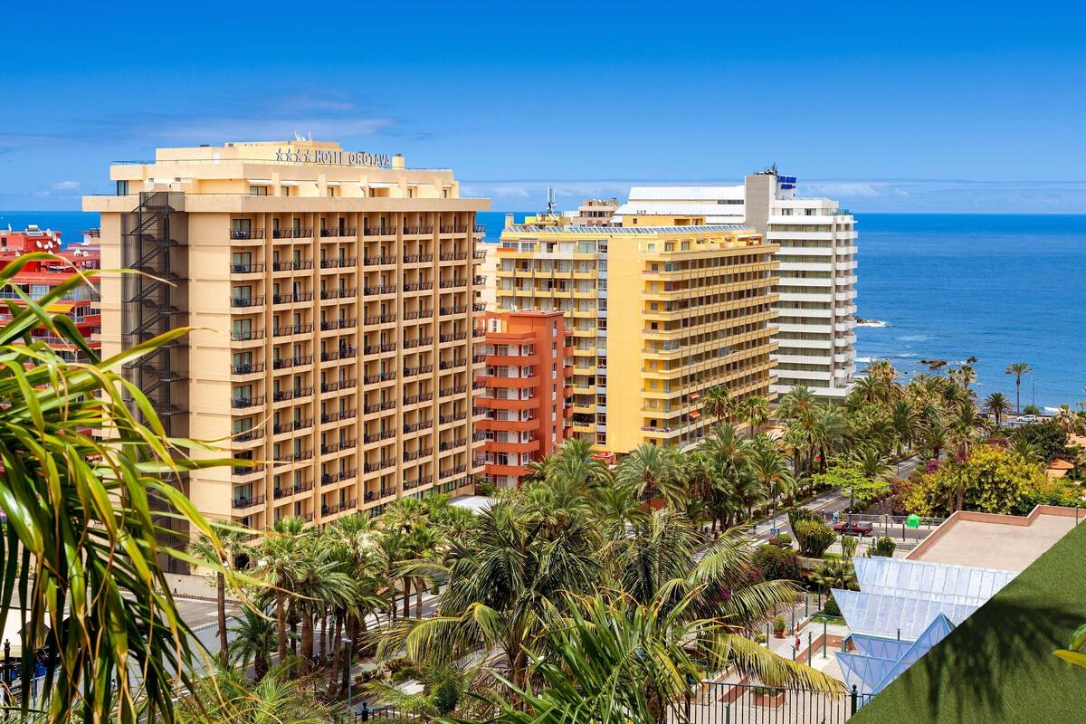 Un hôtel à plusieurs étages, doté de balcons et offrant une vue sur l’océan.