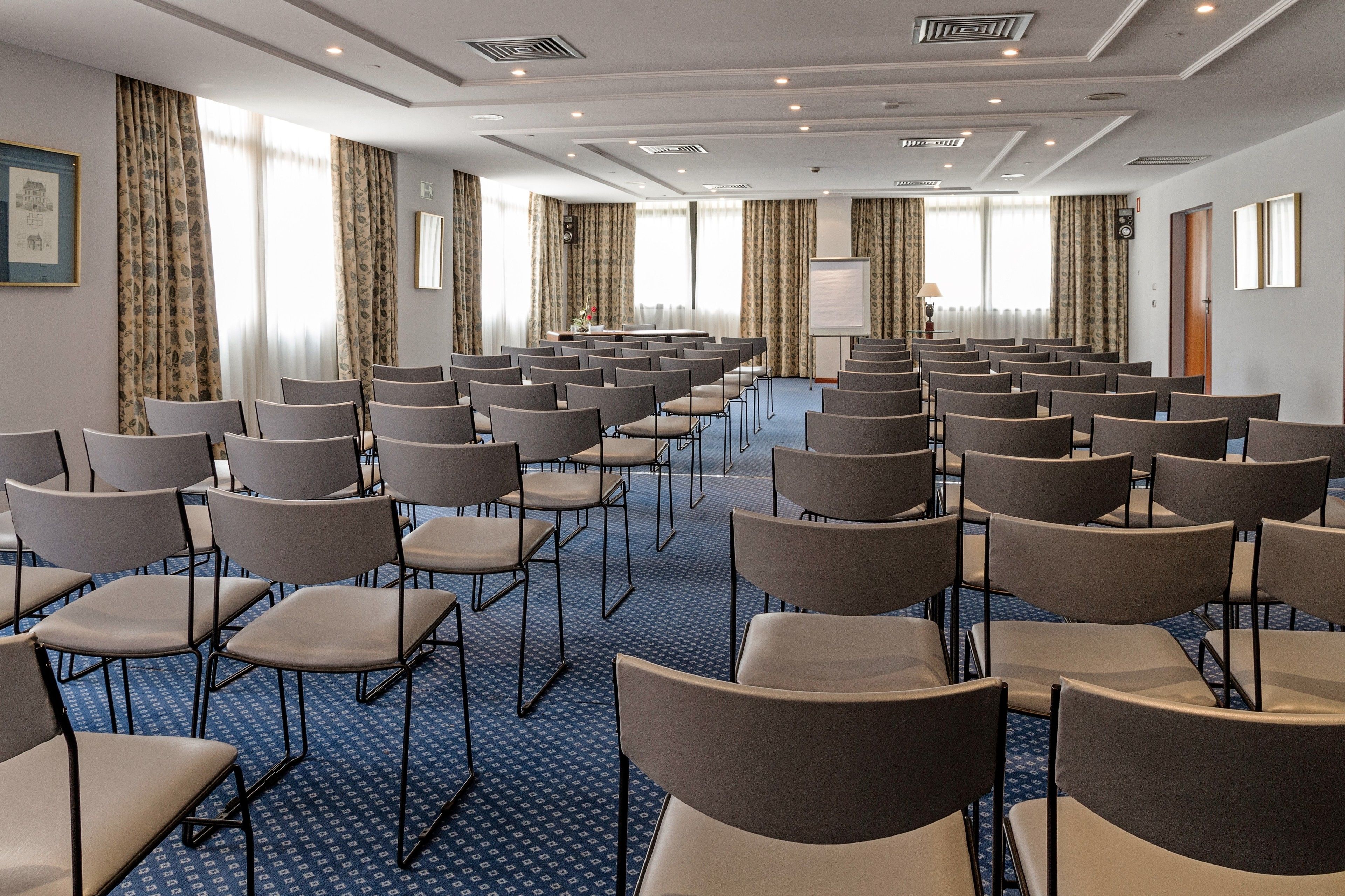 A conference room with rows of chairs, a whiteboard, and a projector screen.
