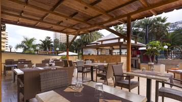 Un espacio al aire libre con patio, mobiliario de mimbre, mesas y sillas.