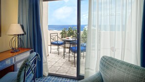 Een balkon met een tafel, stoelen en uitzicht op de oceaan.