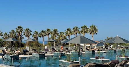 Una piscina techada, una piscina al aire libre, sombrillas