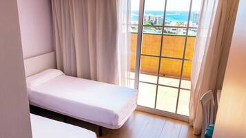 Una habitación de hotel con una cama, una silla y vistas al mar y a edificios.
