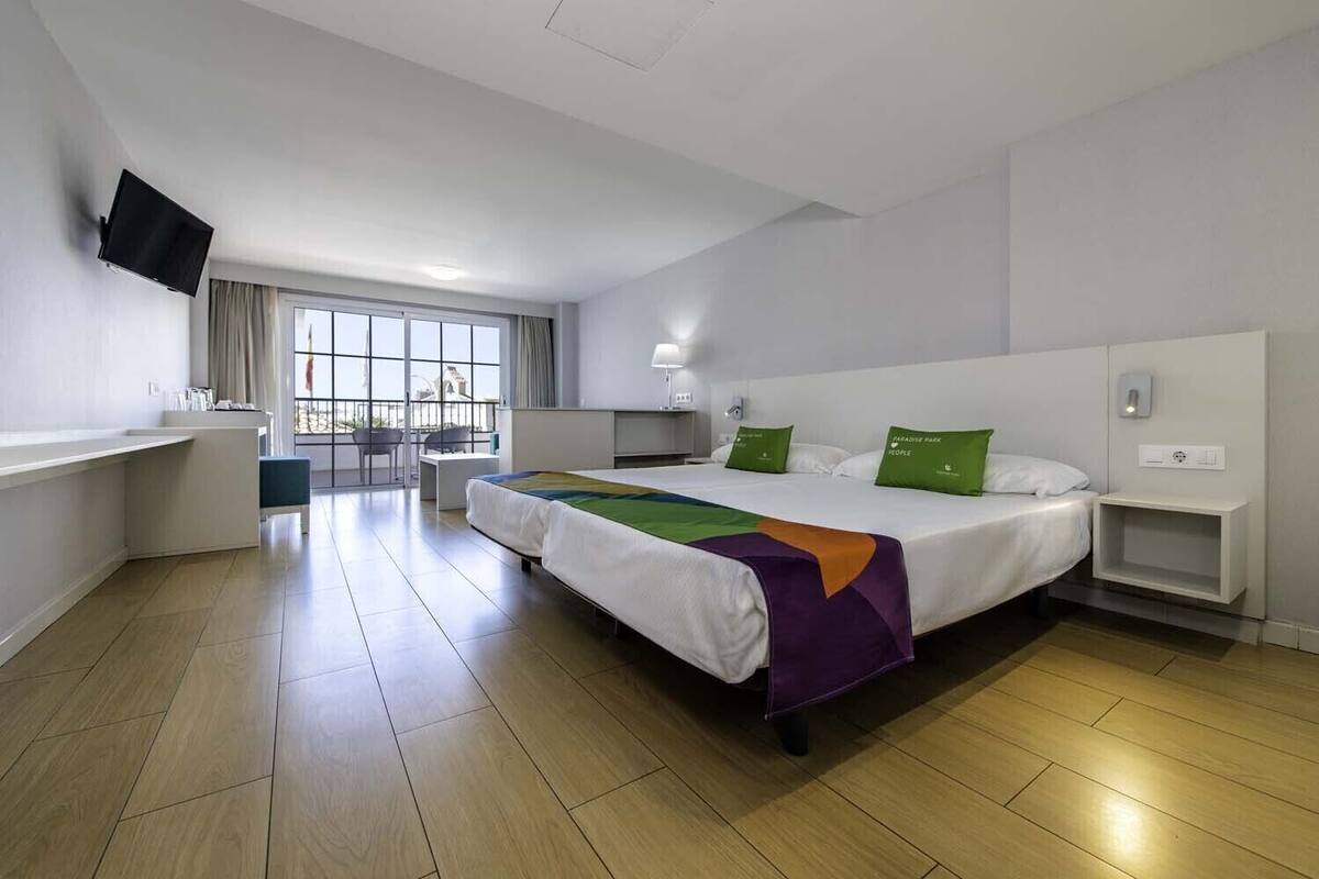 Una habitación de hotel moderna con una cama grande, un escritorio, un televisor de pantalla plana y un balcón con vistas.