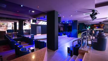 Un hall d’hôtel moderne doté d’un espace salon, d’une scène et d’un bar.