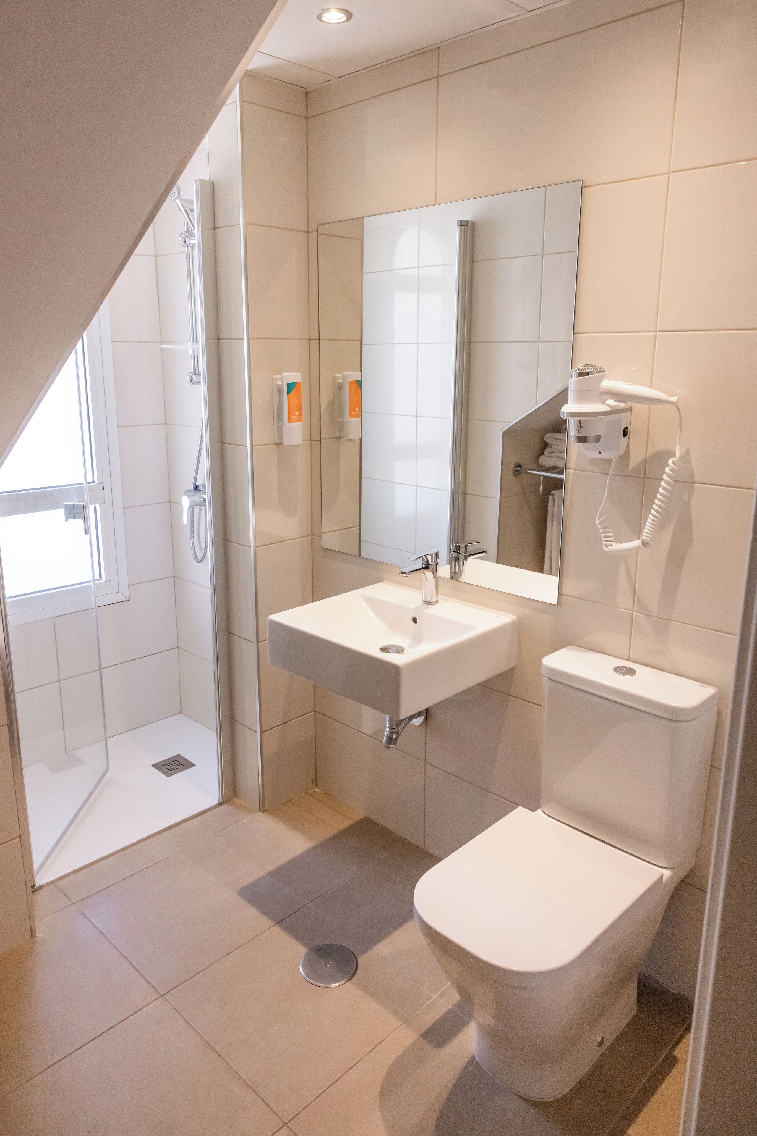 Un baño moderno con ducha, lavabo, inodoro y un espejo grande.