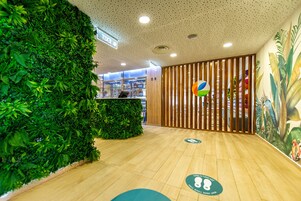 Aula, jossa on vihreä seinä, puulattia ja vastaanottotiski.