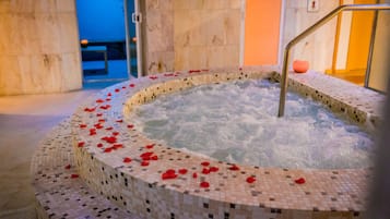 Un jacuzzi con mosaicos y pétalos de rosa.