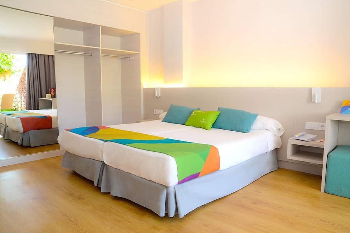 Habitación de hotel con una cama grande, una mesita de noche, un espejo y un armario.