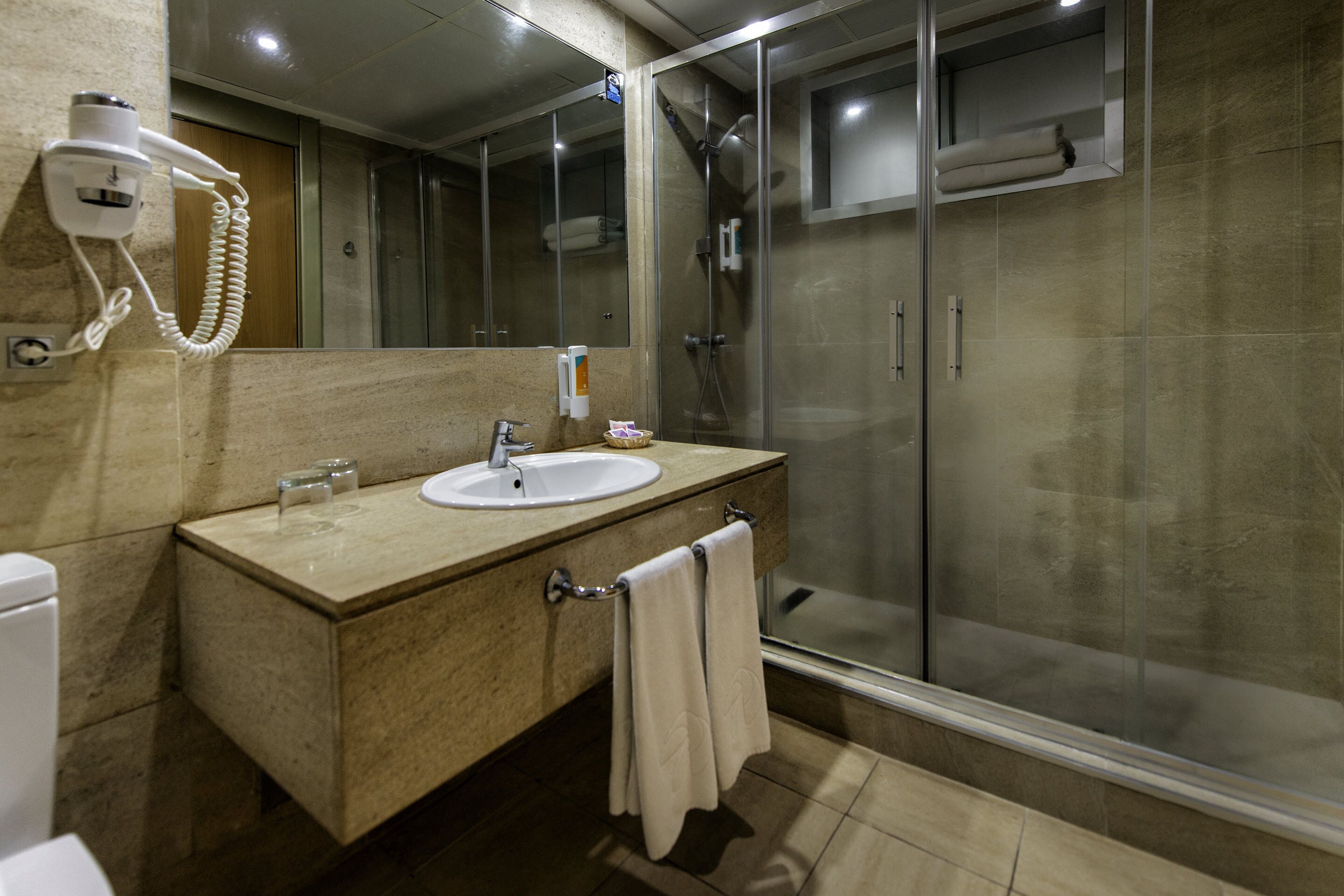 Un baño moderno con lavamanos, espejo y ducha.