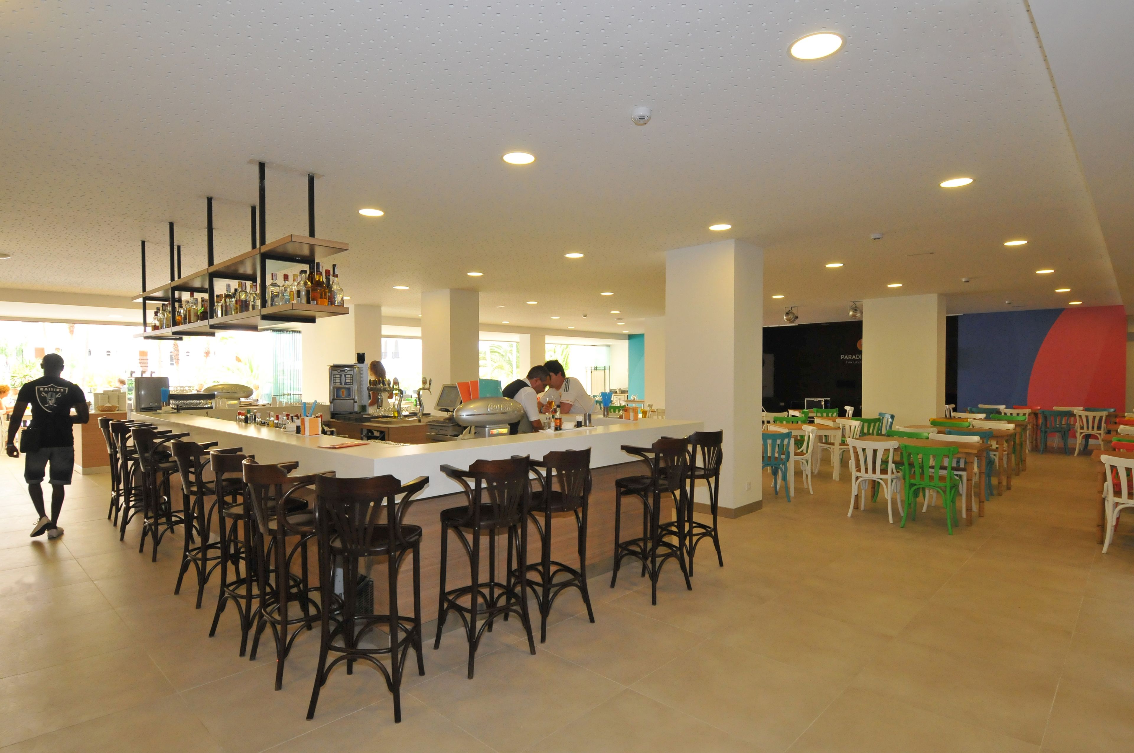 A spacious bar area with high stools and a long counter, surrounded by tables and chairs.