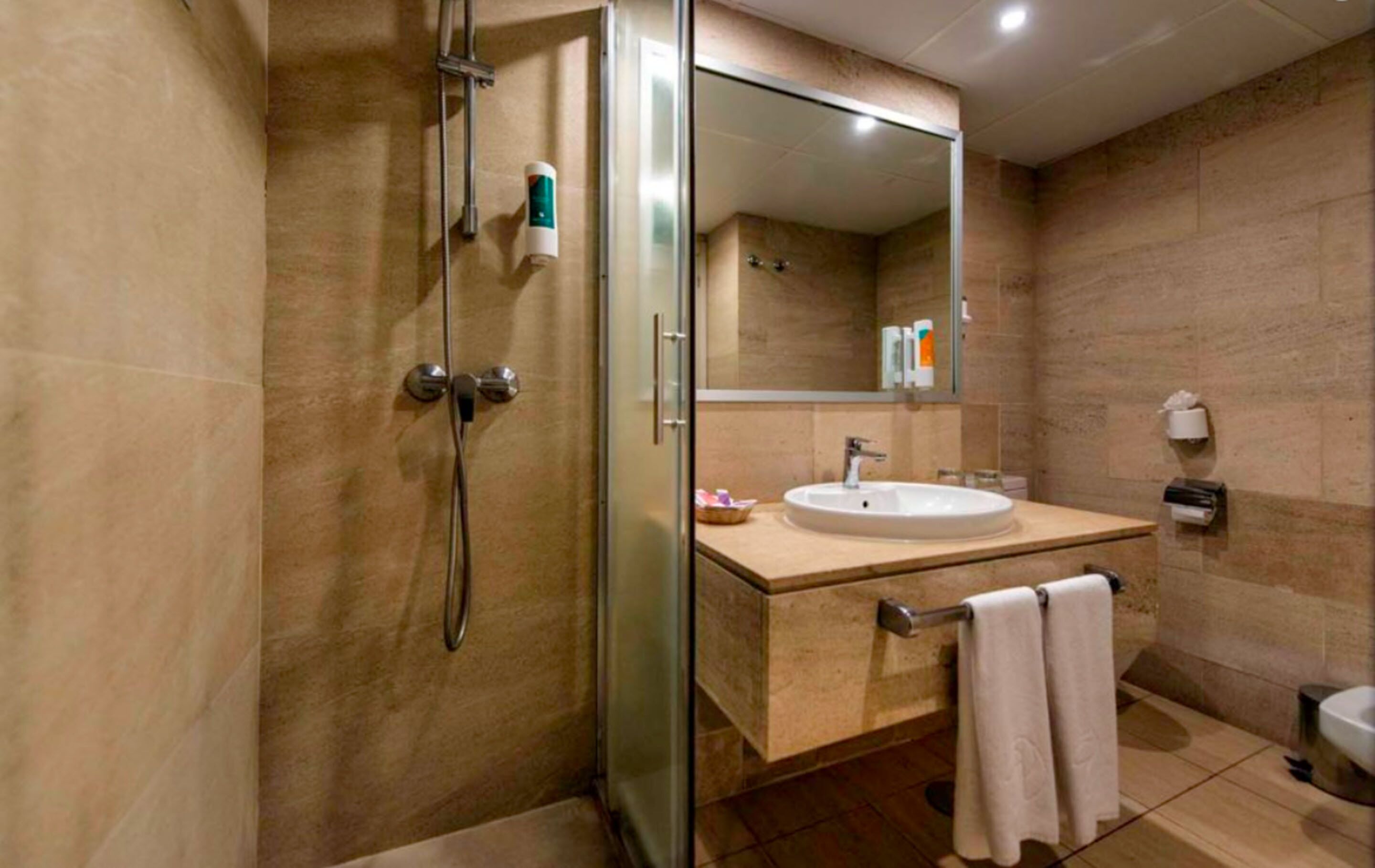 Een moderne badkamer met een douchecabine van glas, een wastafel met spiegel erboven en een handdoekrek.