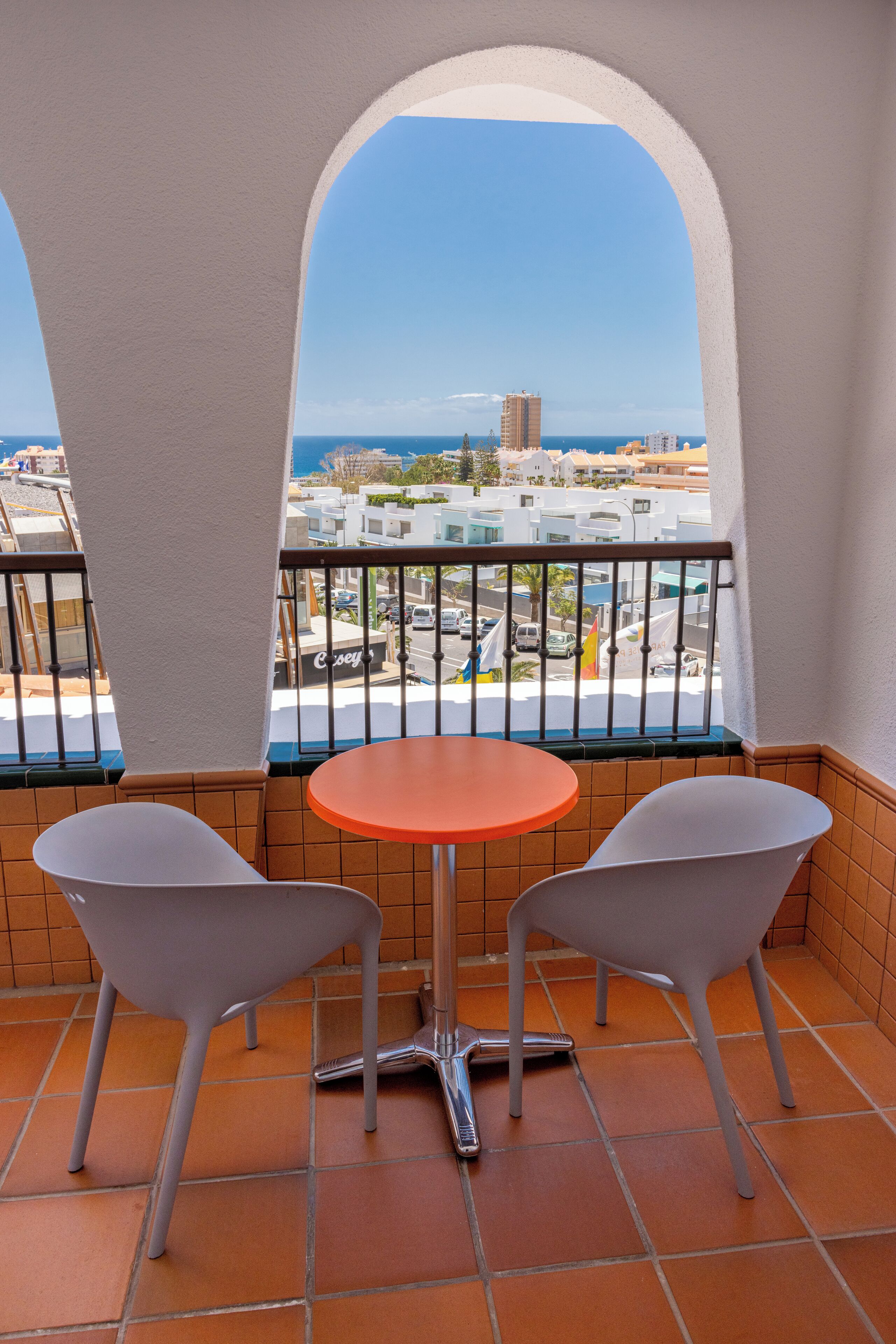Un balcón con dos sillas y una mesa, con vistas a la ciudad y al mar.