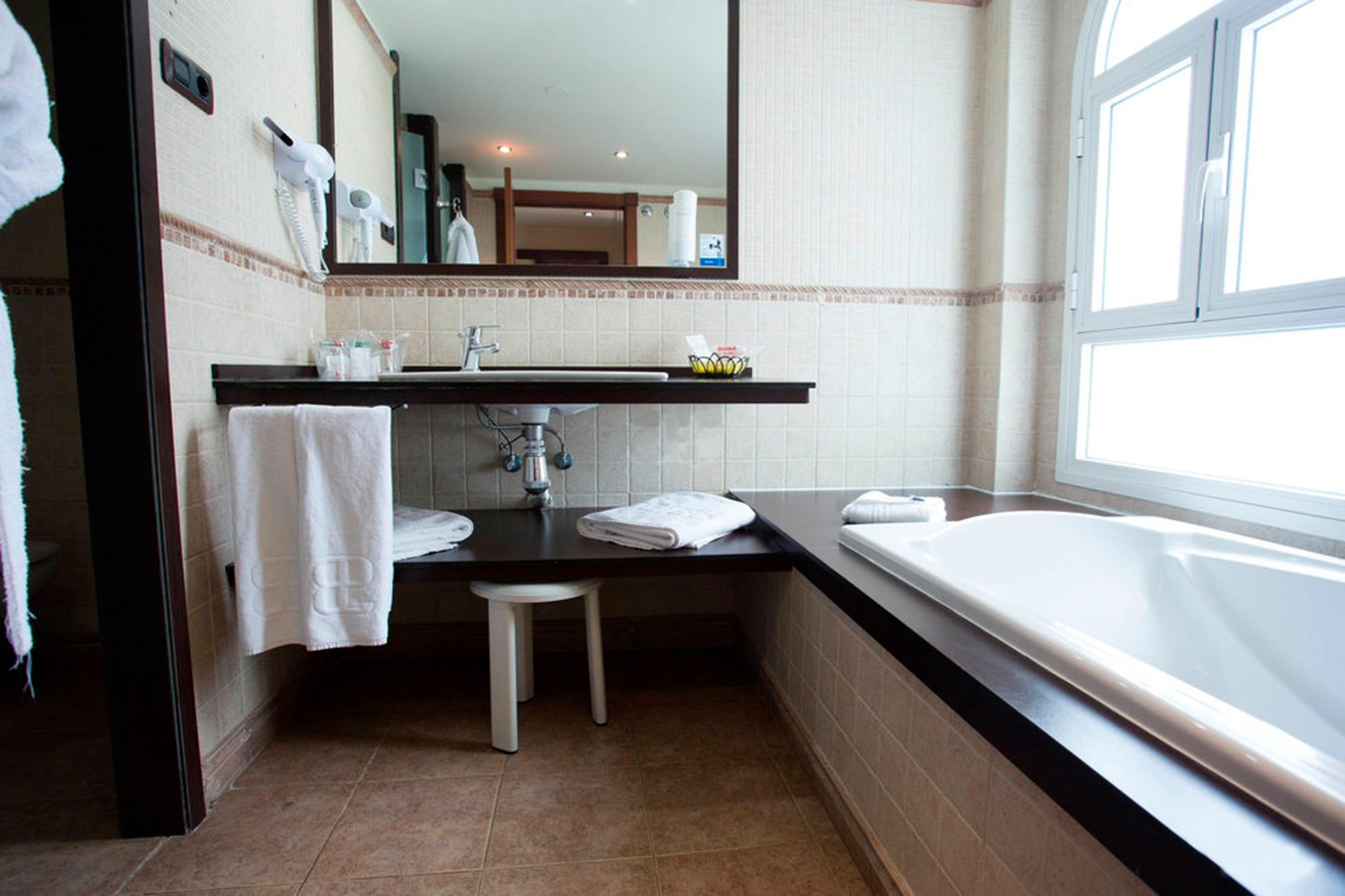 A bathroom with a sink, mirror, towel rack, and bathtub.