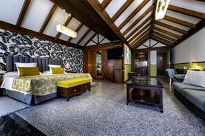 A spacious room with a high ceiling, a bed with a patterned headboard, a sofa, a coffee table, and a kitchen area visible through an open doorway. - Paradise Park Fun Lifestyle Hotel (Arona)