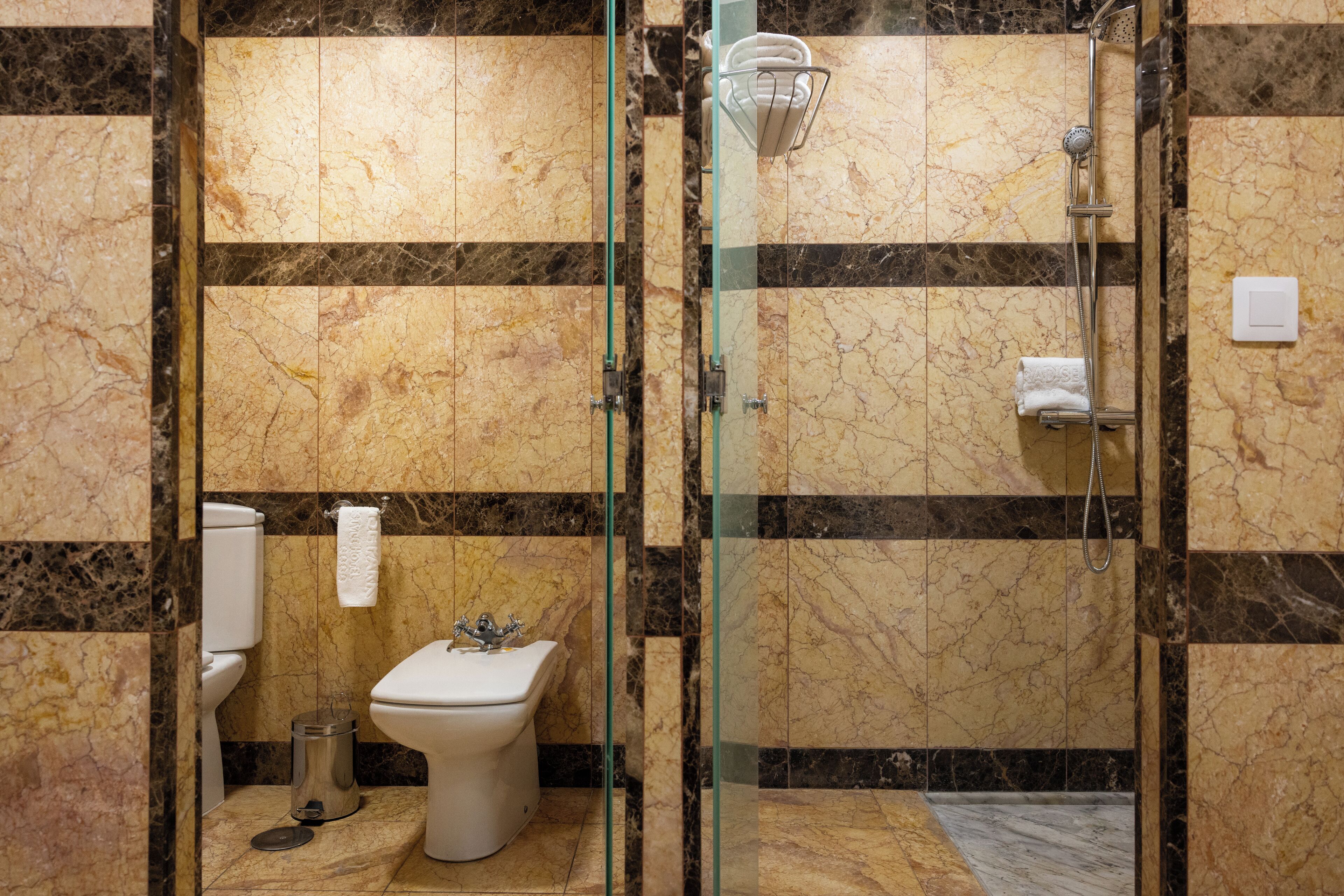 A bathroom with a glass-enclosed shower, a toilet, and a bidet.