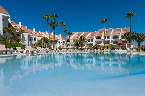 A resort pool area with multiple lounge chairs and palm trees. - Paradise Park Fun Lifestyle Hotel (Arona)