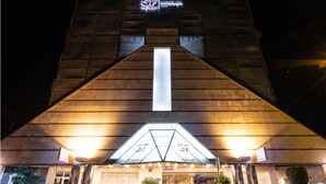 A hotel with a modern architectural design, featuring a prominent triangular entrance and illuminated signage.
