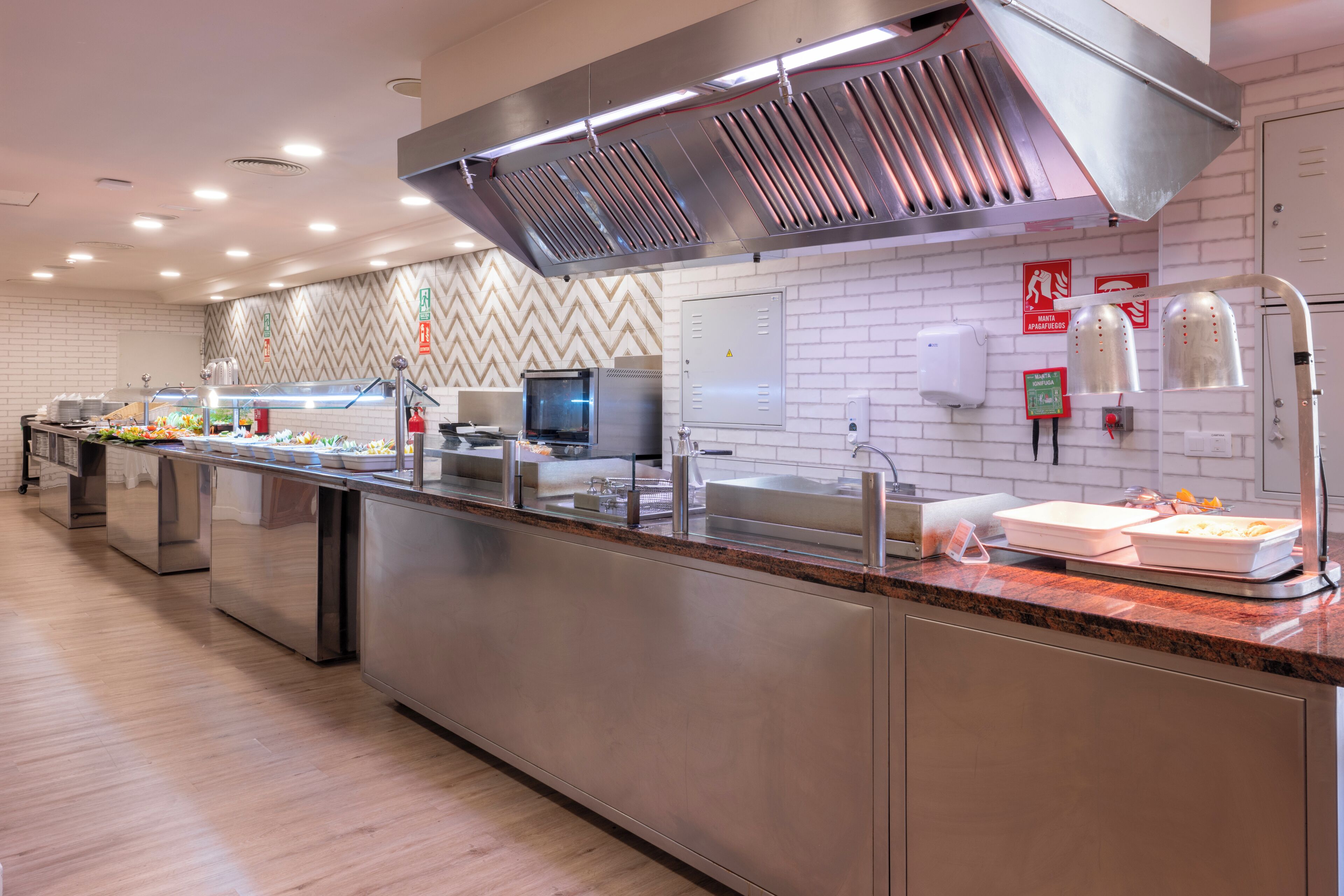 A modern kitchen with stainless steel appliances, a long counter, and a herringbone-patterned backsplash.