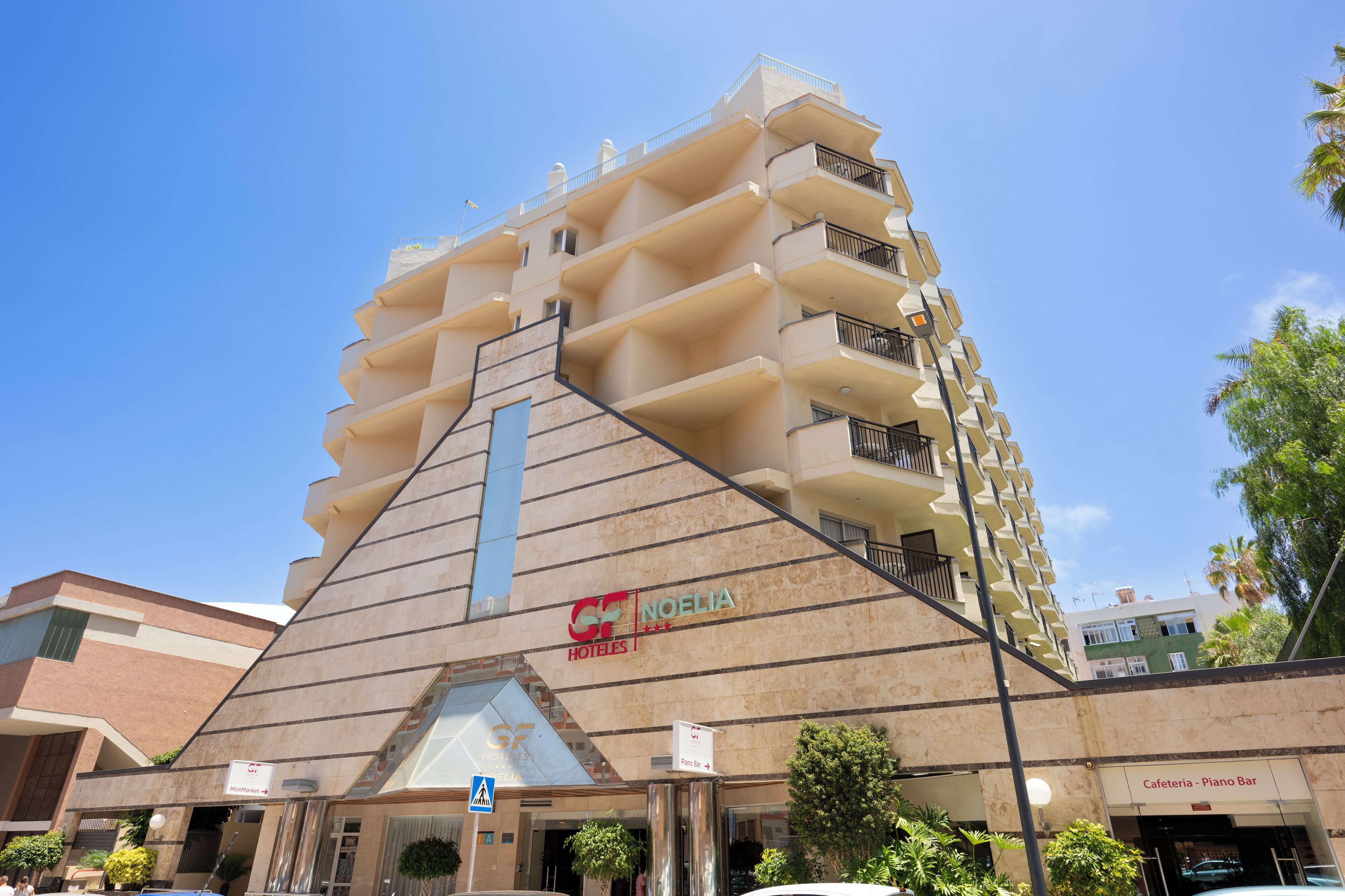 Un hotel con una fachada triangular distintiva, varios balcones y un cartel visible del Hotel Noelia.