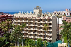 Et hotel med flere etager, altaner, en swimmingpool og havudsigt.