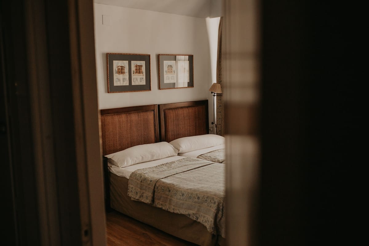 A bedroom with a wooden headboard, a bed with white linens, and two framed pictures on the wall.