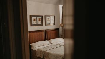 A bedroom with a wooden headboard, a bed with white linens, and two framed pictures on the wall.