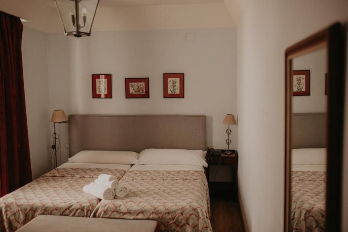 A hotel room with a large bed, two bedside tables, and three framed artworks on the wall.