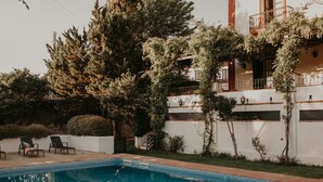 A swimming pool with a tiled edge, surrounded by a white wall and greenery. - Hotel Posada de Valdezufre (Aracena)