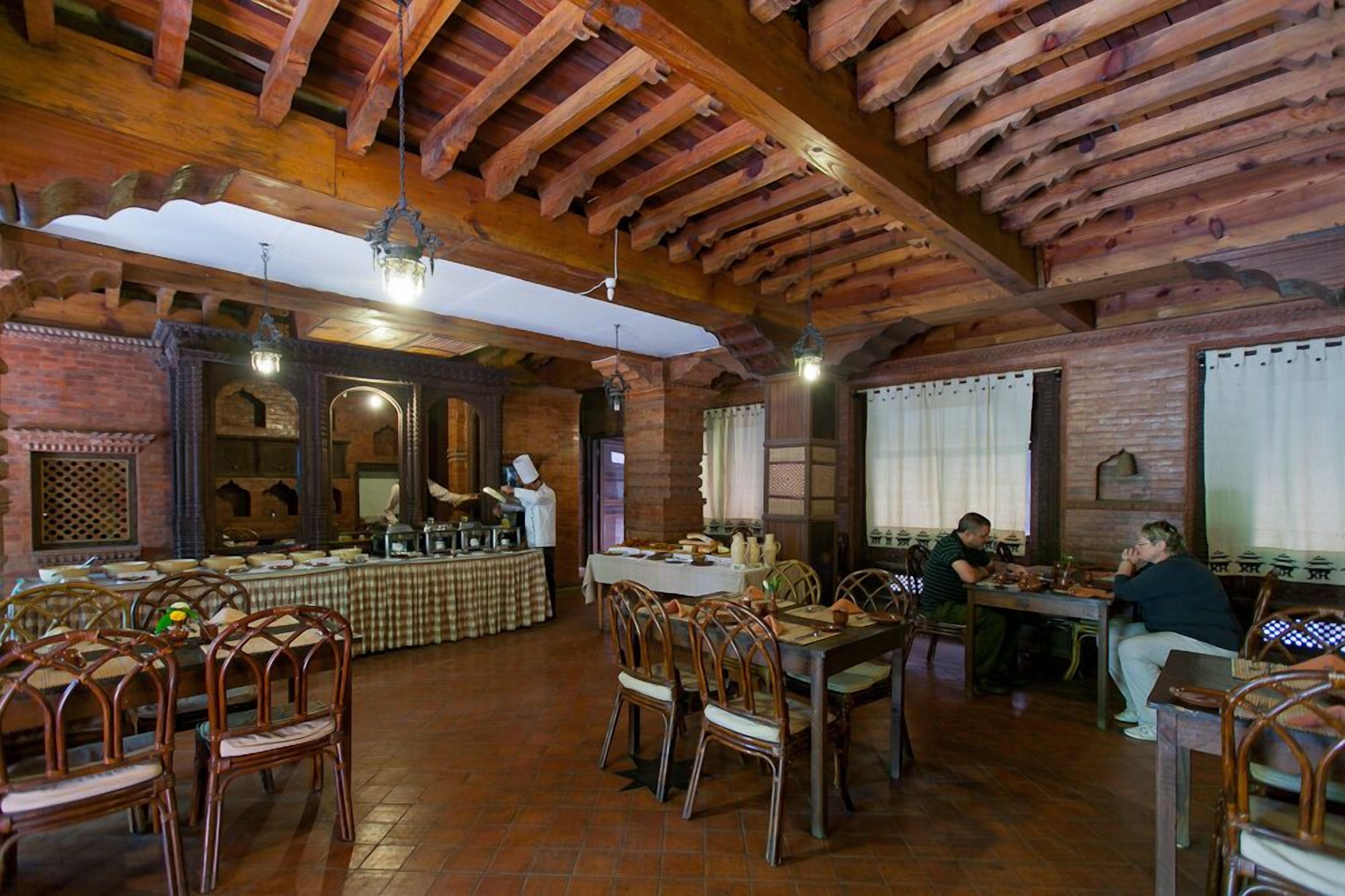 Un restaurante con vigas de madera, paredes de ladrillo y un mantel a cuadros.