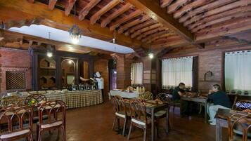 Un restaurante con vigas de madera, paredes de ladrillo y un mantel a cuadros.
