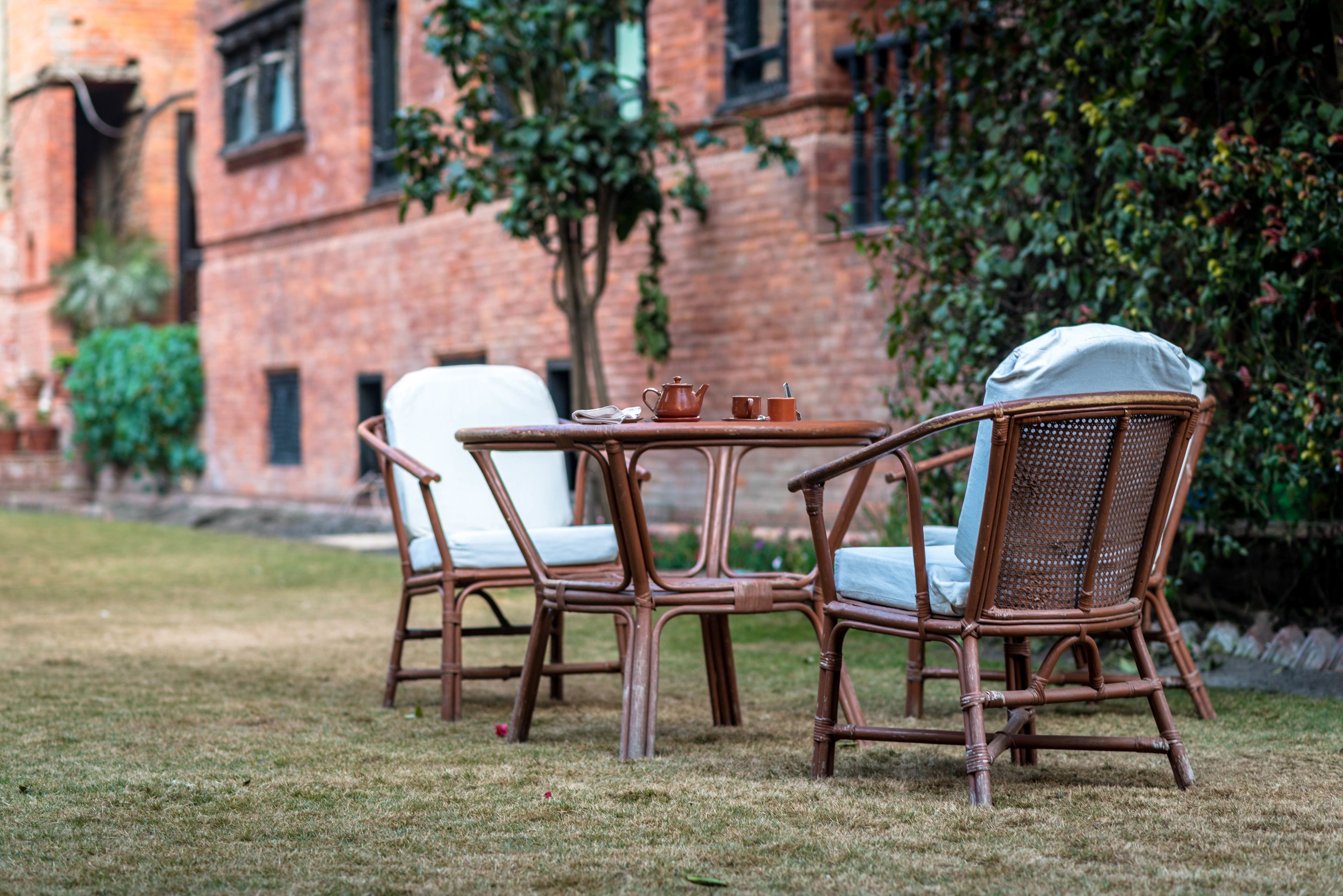 A wicker table and chairs set outdoors with a brick building in the background.