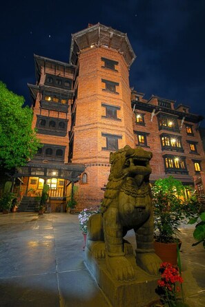 A traditional building with a prominent tower and a lion statue in front. - Kantipur Temple House (Kathmandu)