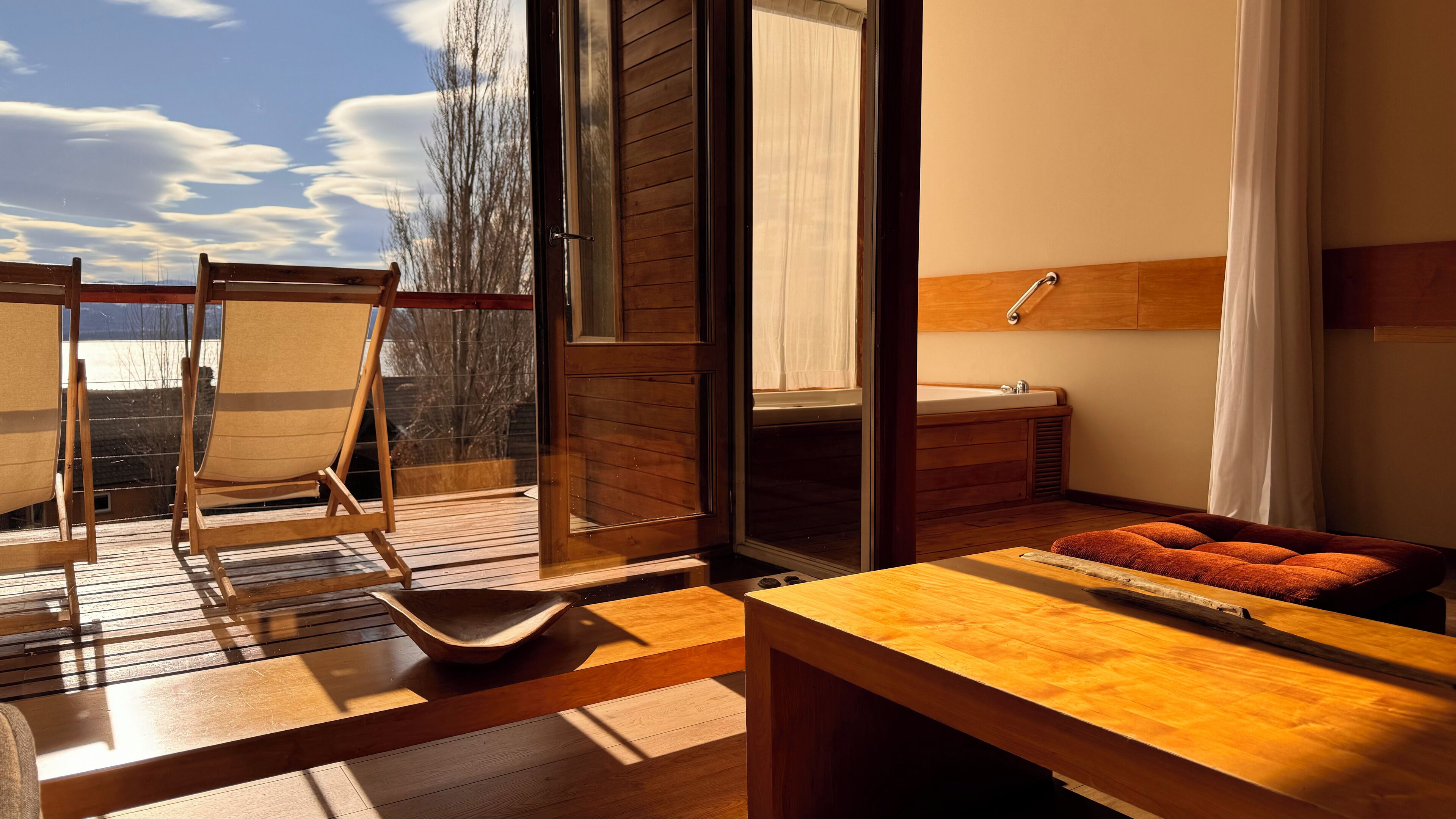 A wooden deck with a seating area, a wooden table, and a view of the sky.