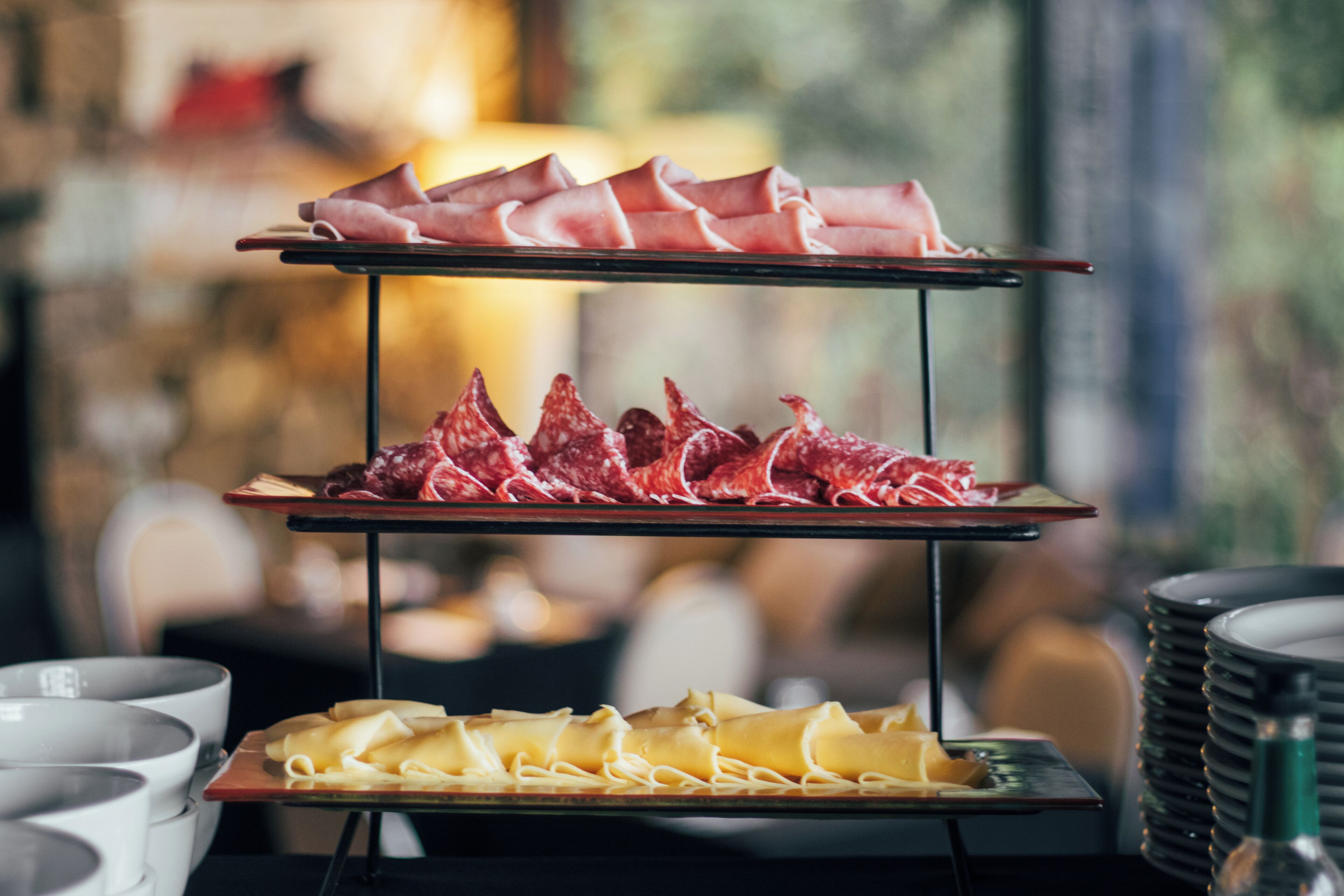 A three-tiered serving tray with various meats and cheeses.