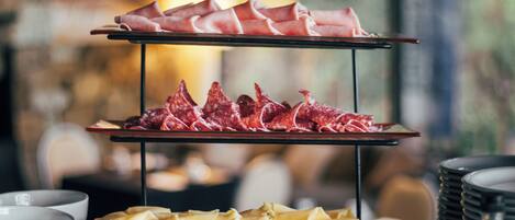 A three-tiered serving tray with various meats and cheeses.